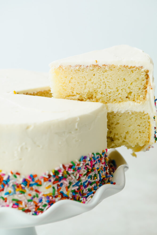 A slice of white cake cut and taken out of the cake. 