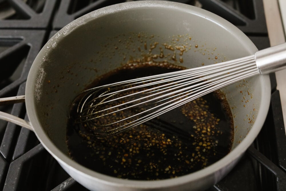 Whisking sauce ingredients together in a pot.