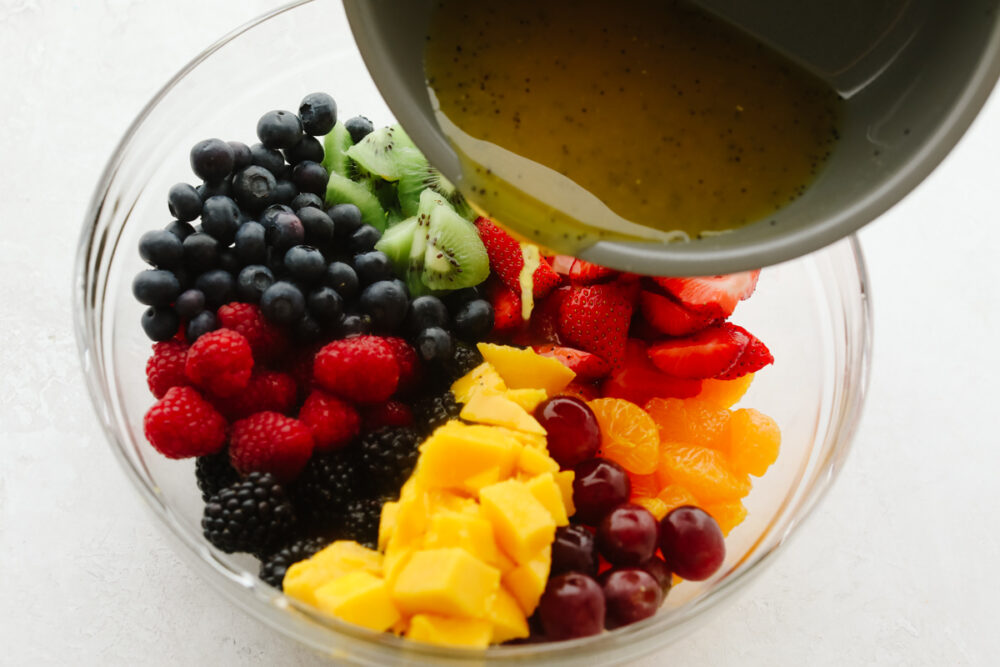 Pouring lime dressing over fruits.