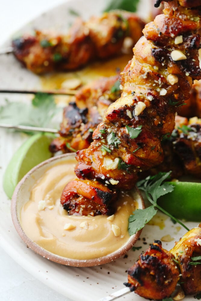 Dunking a chicken satay skewer in peanut sauce. 