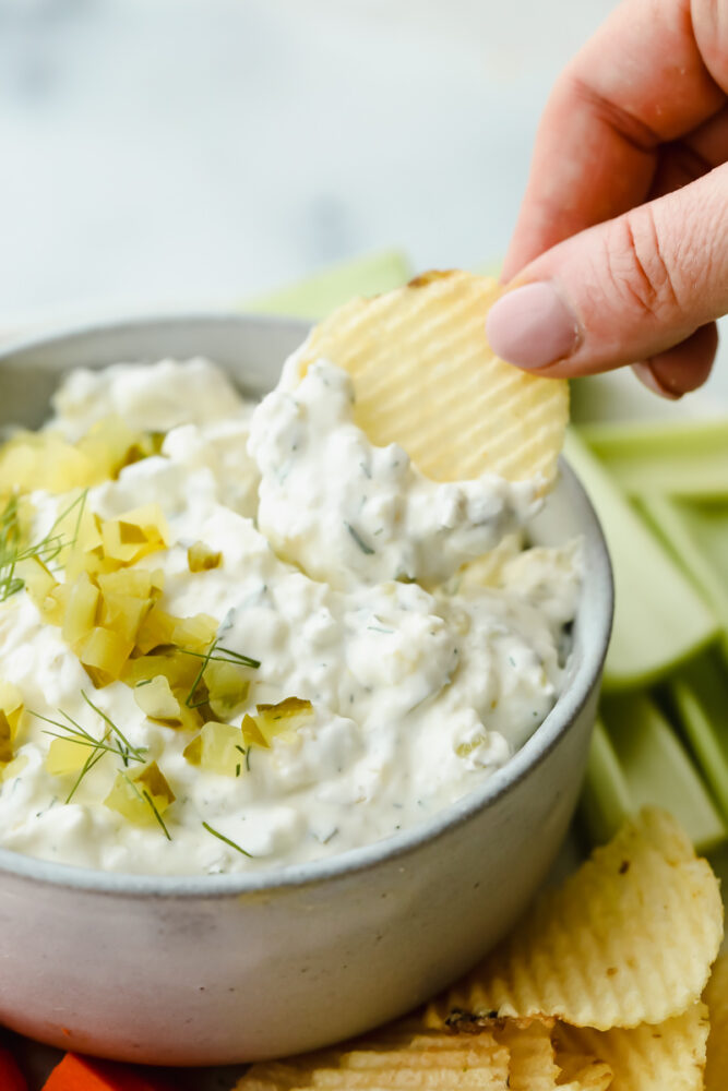 Putting dill pickle dip on a potato chip.