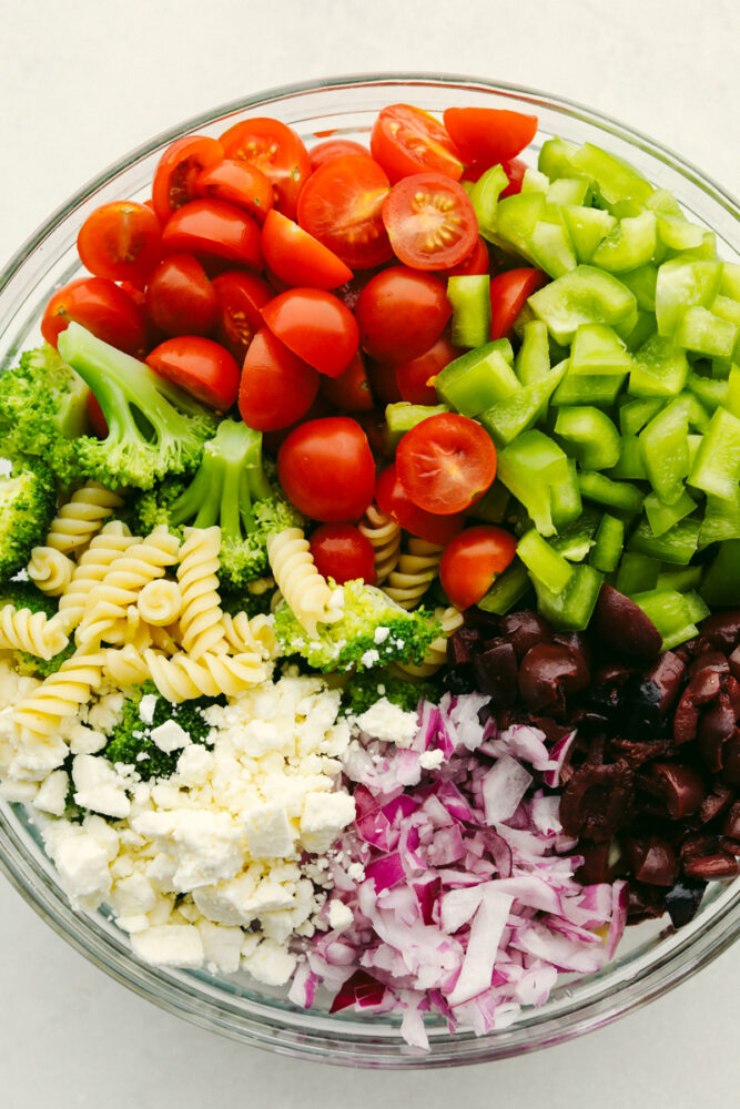 A variety of vegetables and cheese in a bowl, ready to be mixed.