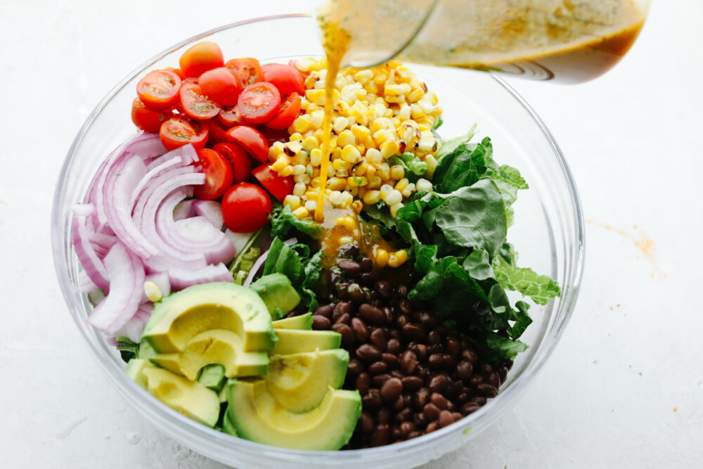 Pouring chipotle dressing over vegetbles.