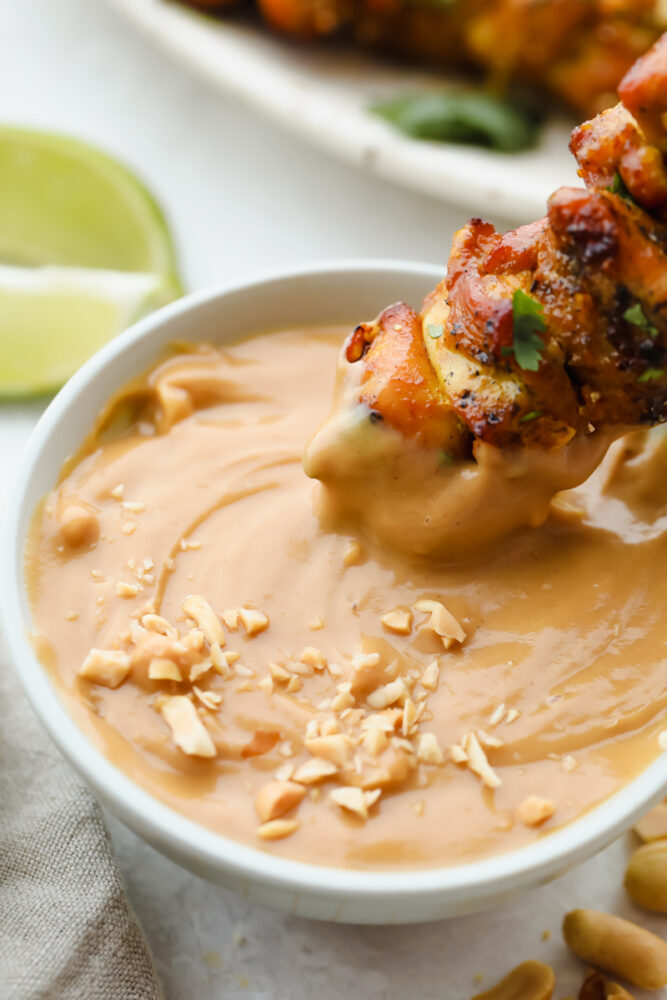 Dipping a skewer in Peanut Sauce.