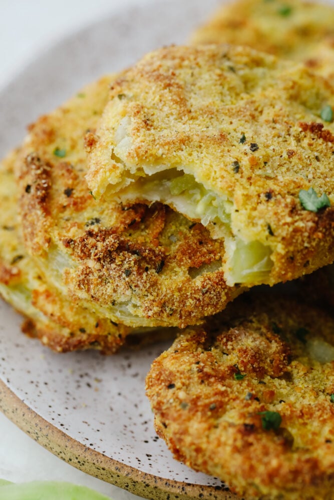 A fried green tomato with a bite taken out of it. 