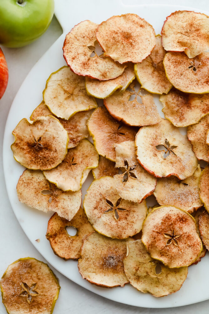 Crisp baked cinnamon sugar apple chips on a white plate. 