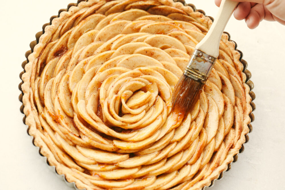 Brushing the top of the pastry with apricot preserves.