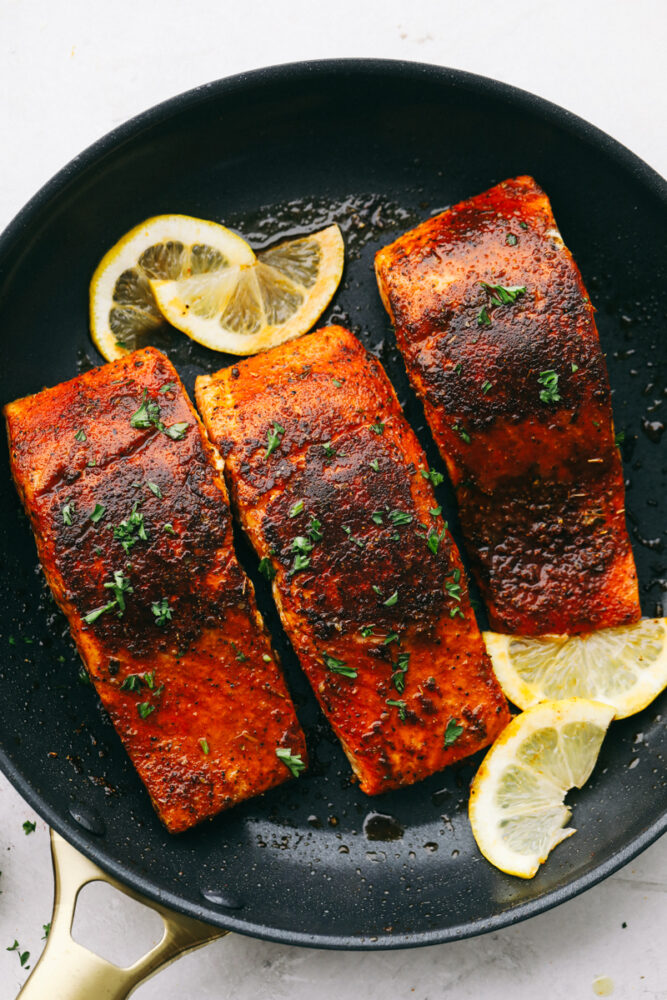 Slices of lemon garnish fillets of blackened salmon. 