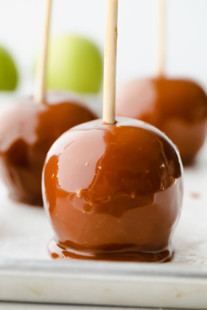 3 caramel apples on parchment paper.