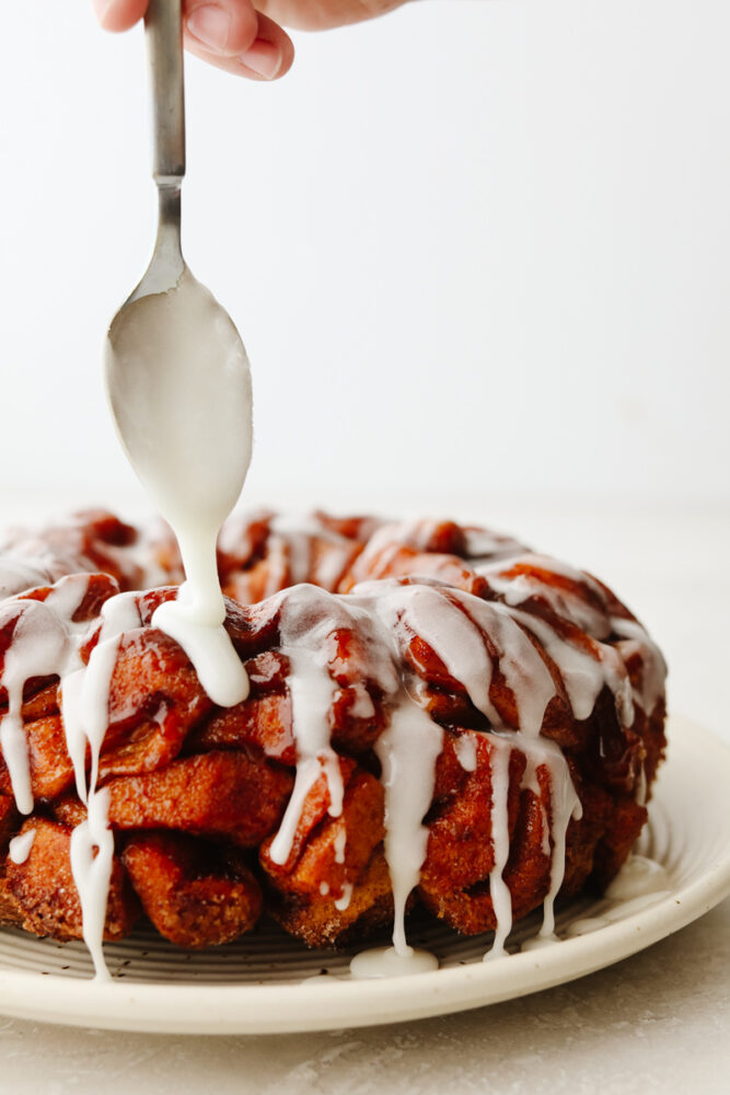 Drizzling icing on cinnamon roll monkey bread.