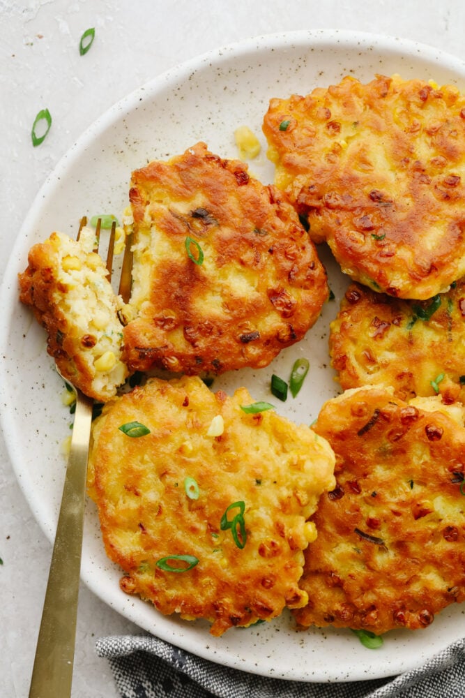 Fritters on a plate being cut with a fork. 