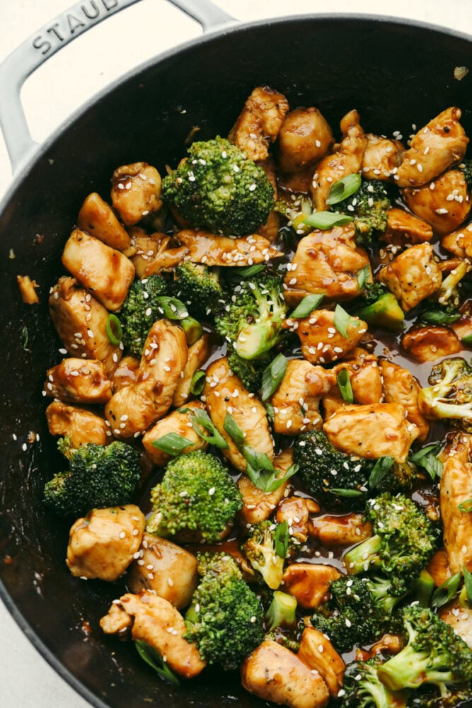 Chicken and broccoli topped with sauce in a skillet.