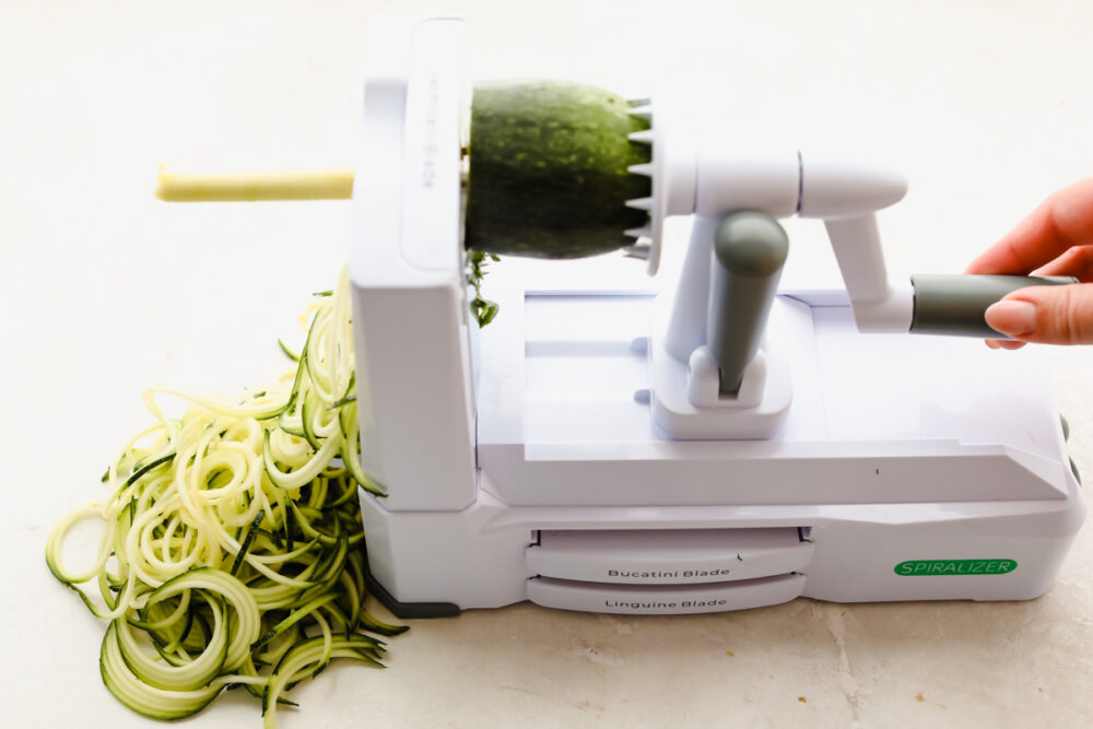 Using a spiralizer to prepare zucchini noodles.