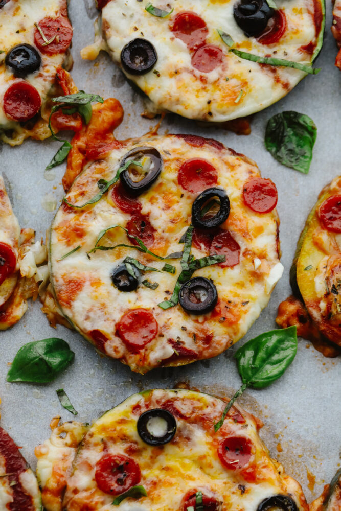 Close-up of zucchini pizza bites with basil garnish.