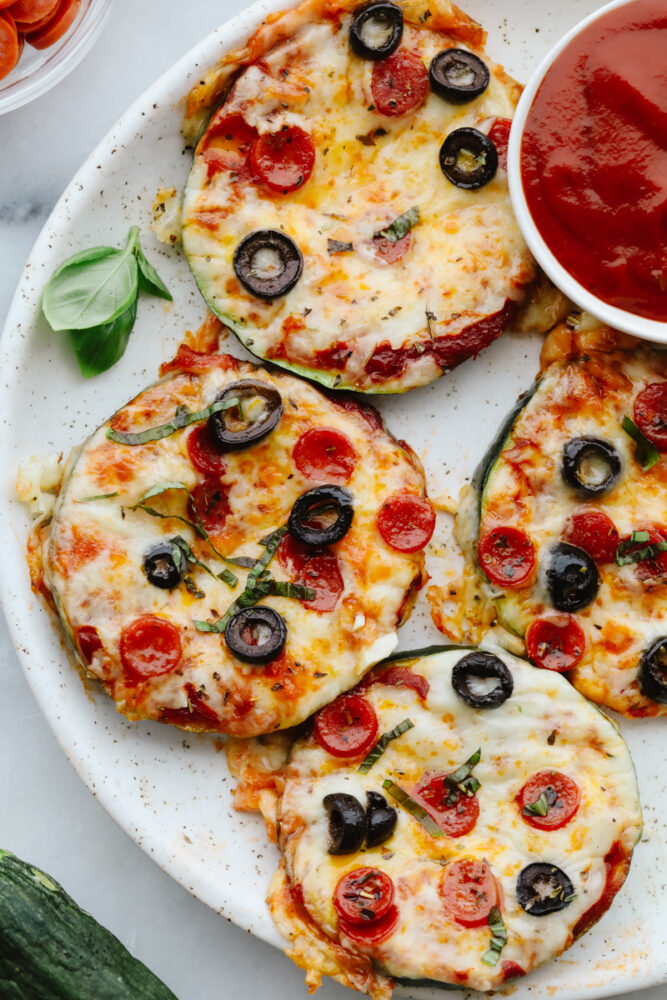 Pizza bites on a white plate with marinara dipping sauce.