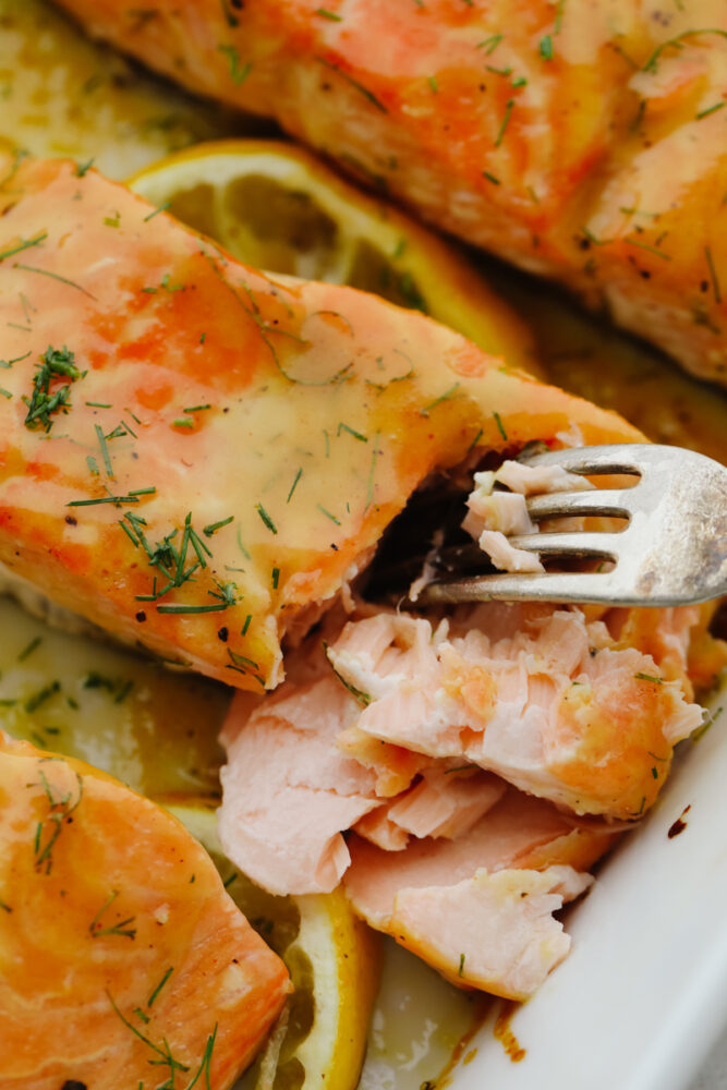 A fork digging in to baked honey mustard salmon