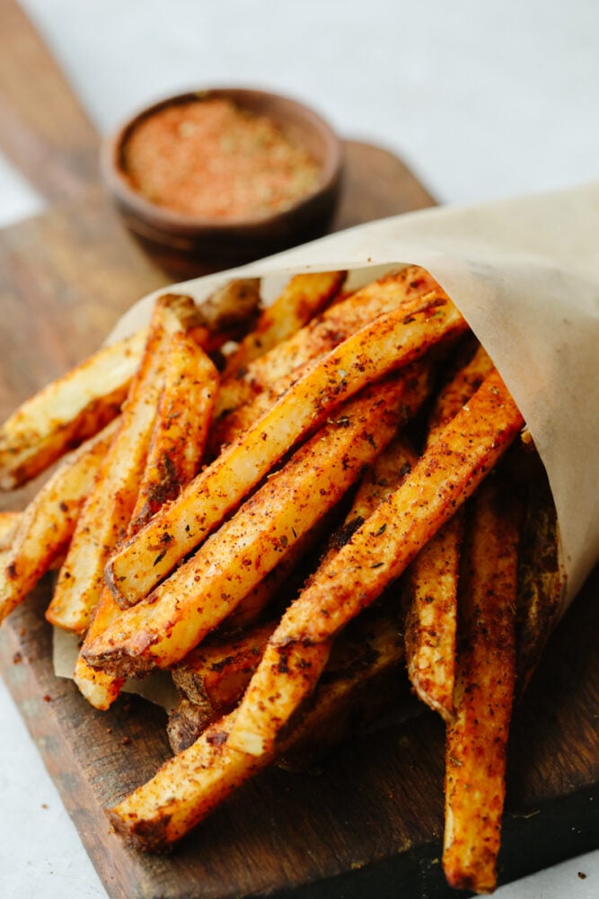 Cajun fries wrapped up in parchment paper in a cone. 