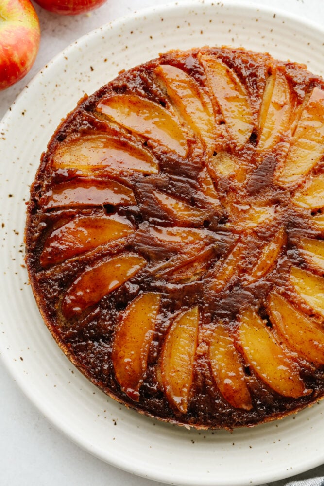 A full caramel apple upside-down cake on a white serving dish.