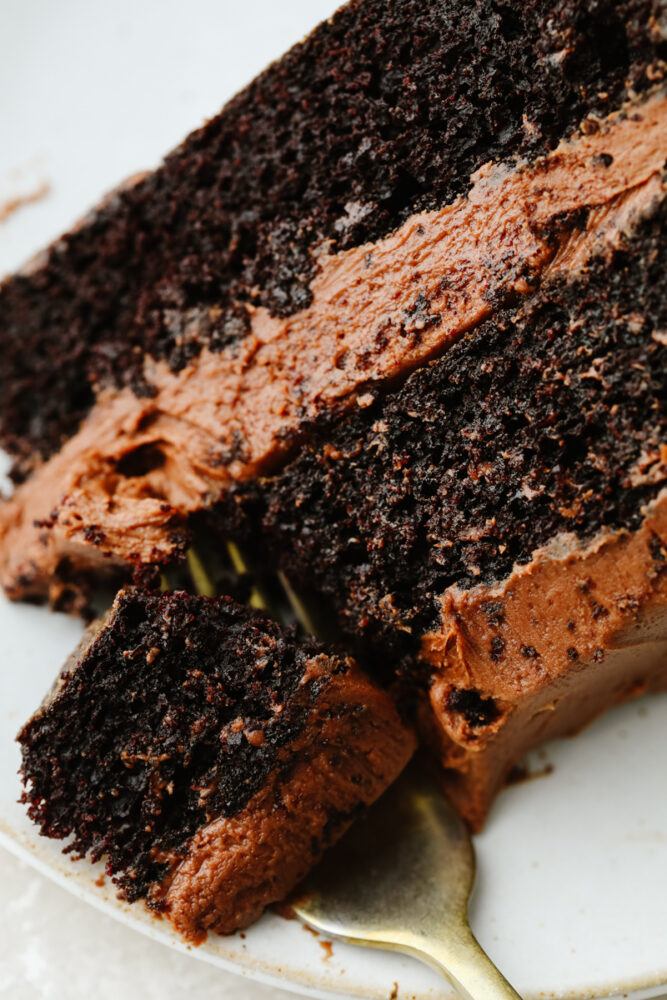 A slice of chocolate cake being cut with  fork. 