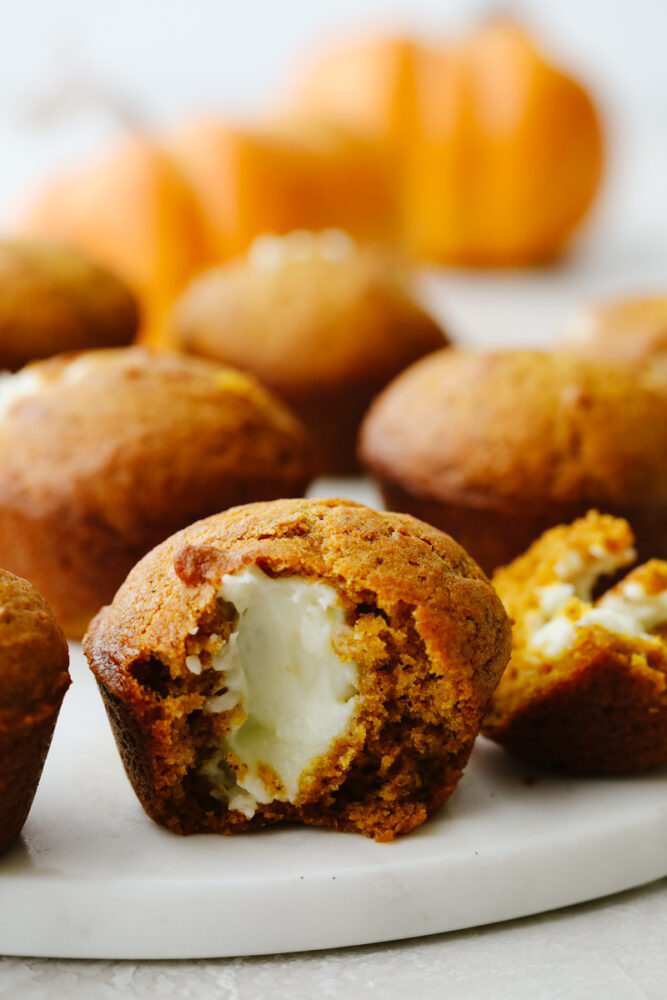 Pumpkin muffin cut in half showing cream cheese in the middle. 