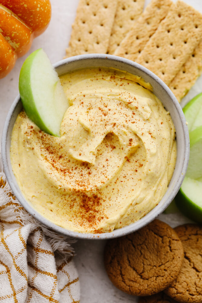 Pumpkin pie dip in a bowl with an apple slice in it. 