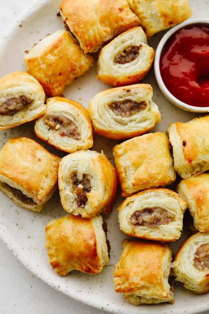 Sausage rolls on a platter with ketchup. 