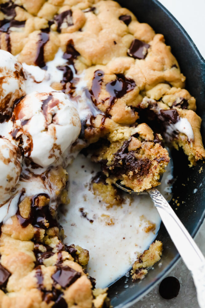 A skillet cookie being scooped up with a spoon. 