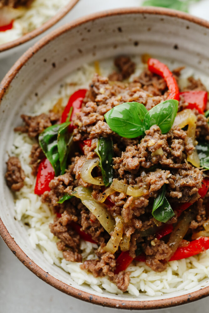 A close up of Thai basil beef on rice, in a bowl. 