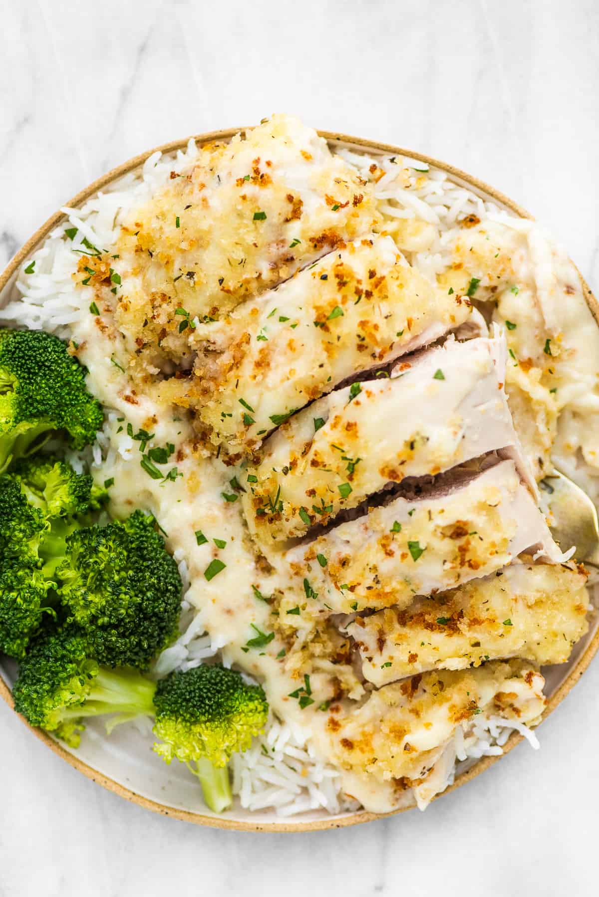 Swiss chicken bake on a plate with rice and broccoli.