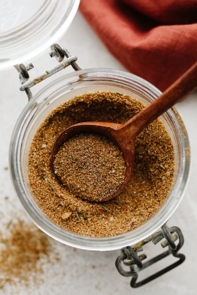 Jerk seasoning in a jar with wooden spoon. 