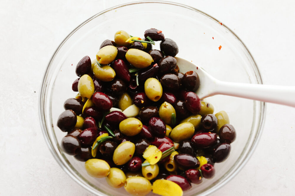 Mixing olives with herbs, lemon, and spices.