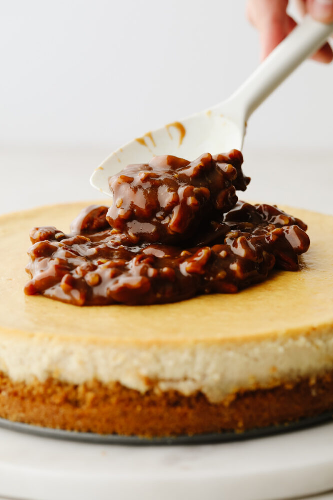 Putting pecan topping on cheesecake.