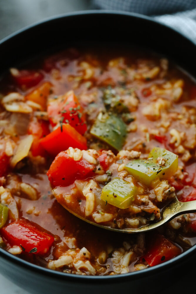 Zoomed in picture of a spoon scooping up some stuffed pepper soup. 