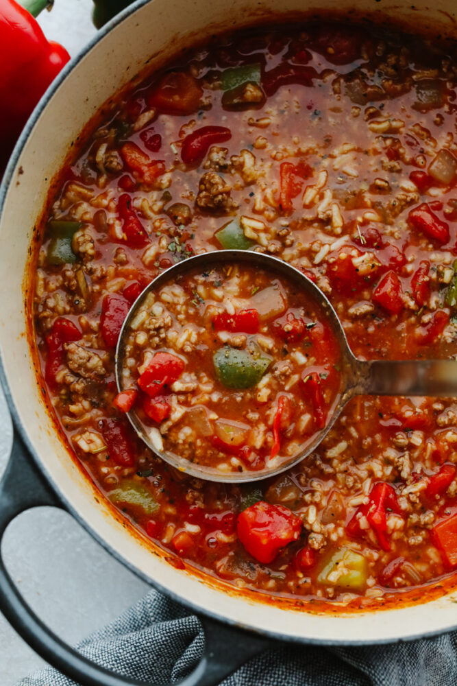 A ladle in a pot of stuffed pepper soup. 