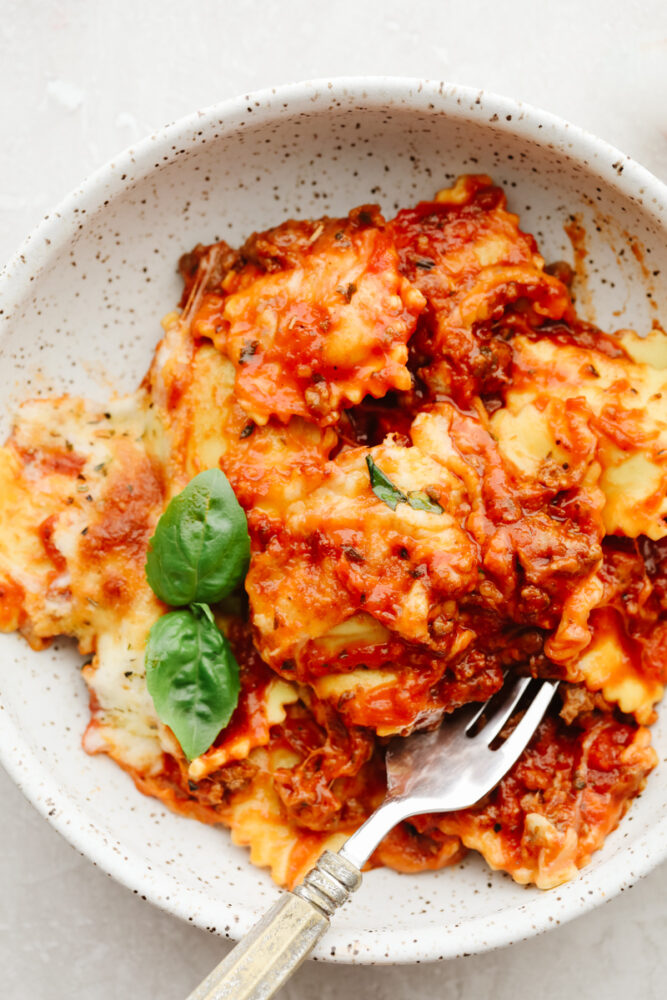 Baked ravioli in a white stoneware bowl.