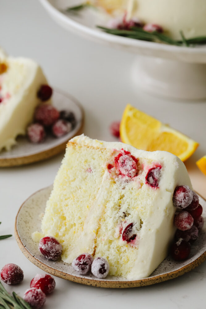 A slice of cranberry Christmas cake on a stoneware plate.