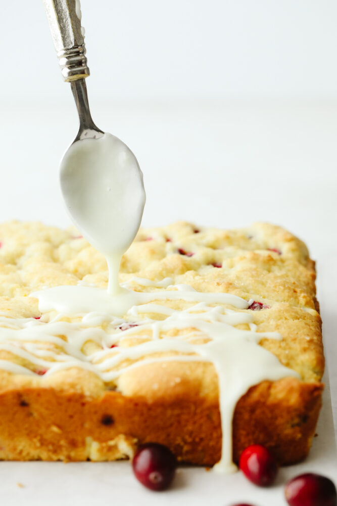 An orange glaze being drizzled on the cake. 