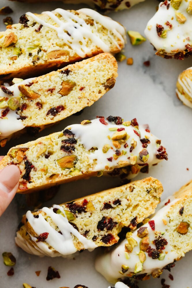 Closeup of biscotti, dipped in white chocolate and topped with pistachio and cranberry pieces.