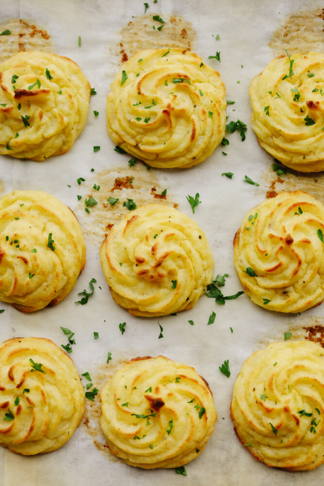 Baked duchess potatoes on parchment paper.