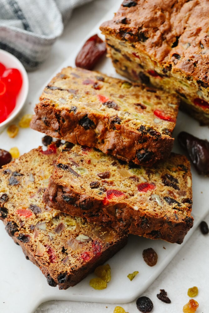 Fruit cake cut into slices on a white serving dish.