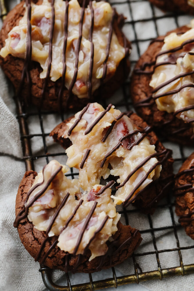 A German chocolate cookie broken in half on a cooling rack.