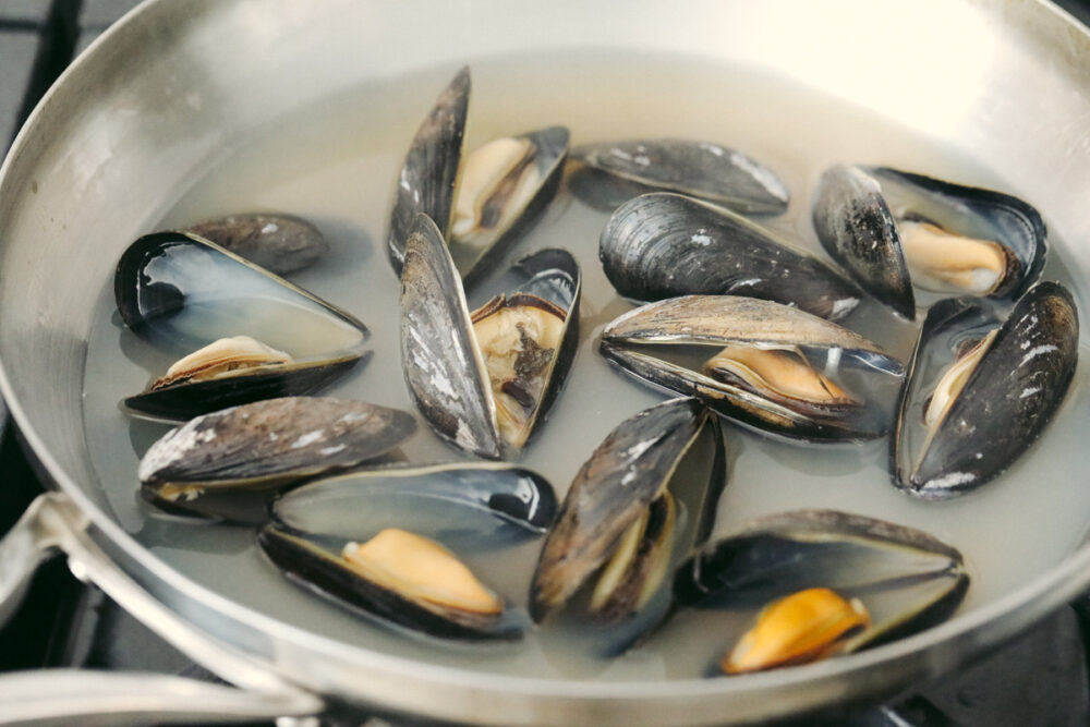 Mussels that are fully cooked and open in a pan. 