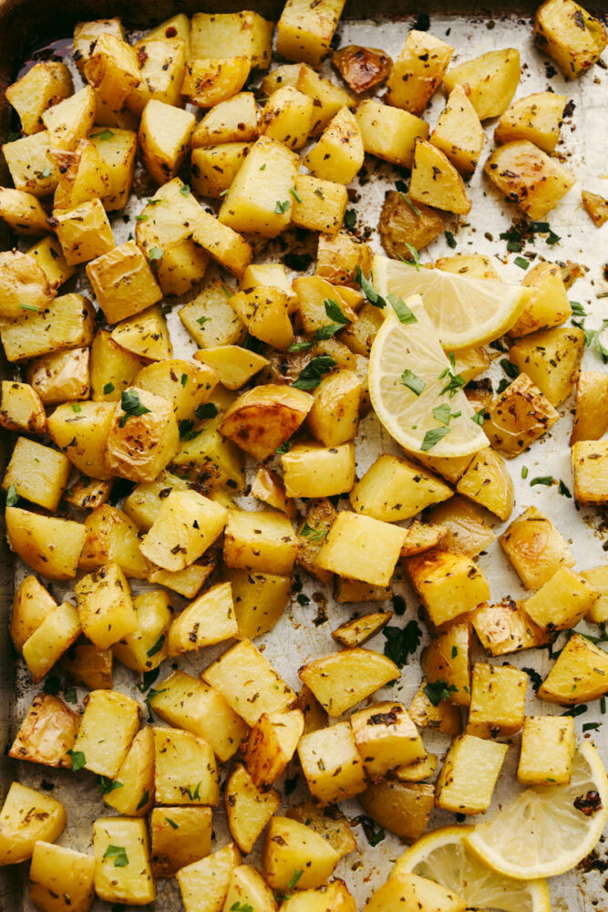 Cubed potatoes seasoned on a baking sheet. 