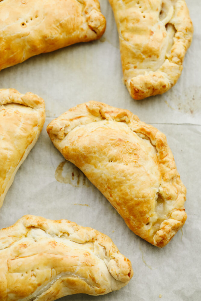 Cornish pasties cooked and on a pan with parchment paper. 