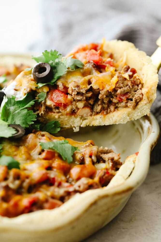 A slice of taco pie being taken out of the pan. 