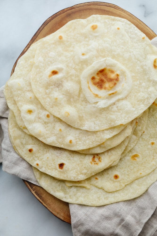 A stack of homemade tortillas on a platter. 