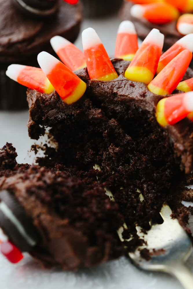 A chocolate cupcake with a fork cutting into it. 