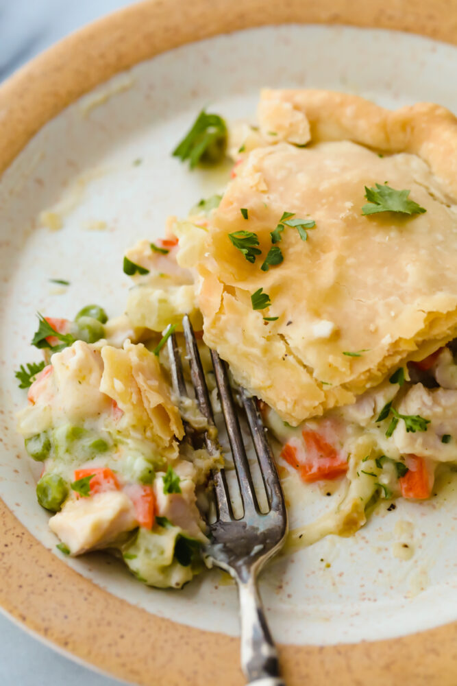 Turkey pot pie on a plate with a fork cutting into it. 