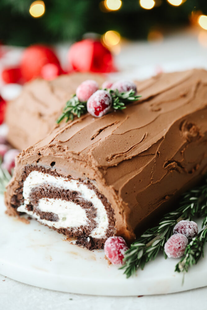 A yule log cake on a platter with garnish. 