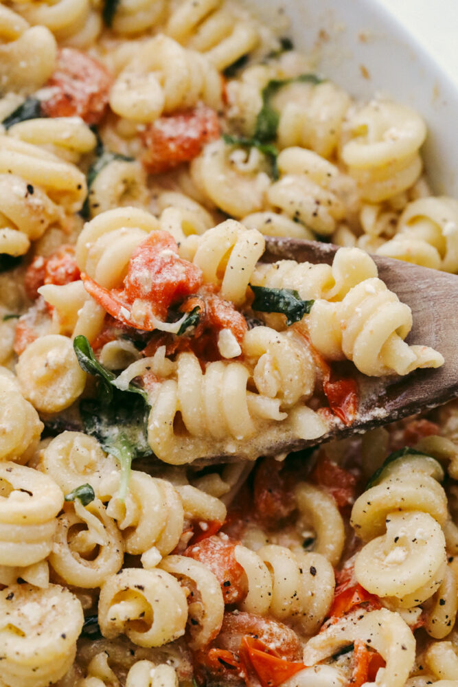 A wooded spoon dishing up baked feta pasta. 